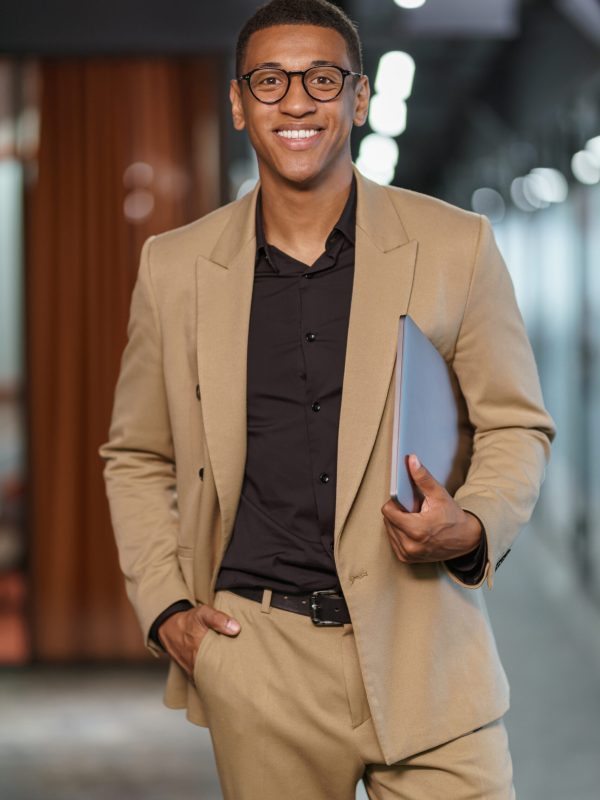 Handsome smiling african businessman with documents standing in modern coworking. High quality photo